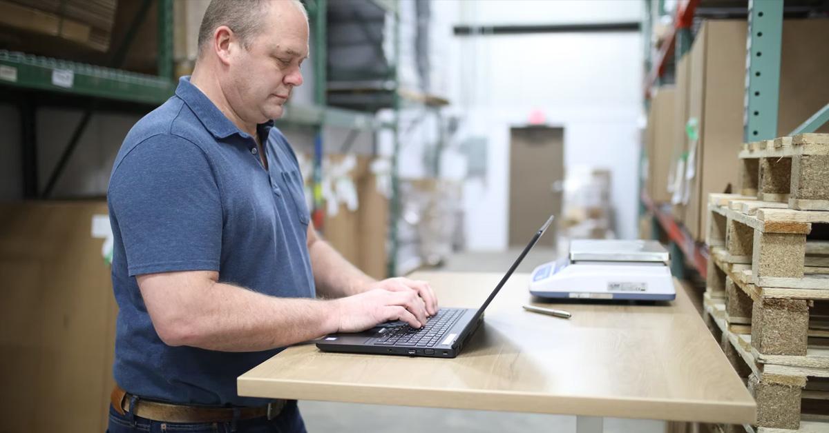 Employee working on a laptop in a warehouse