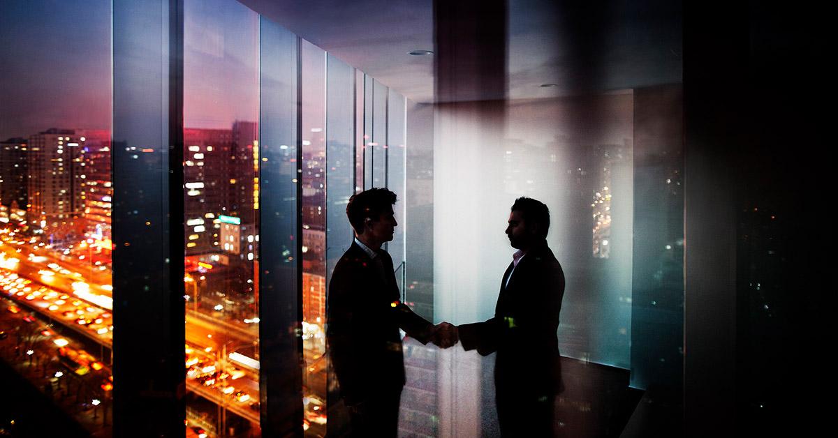 men standing in a room overlooking the city and shaking hands