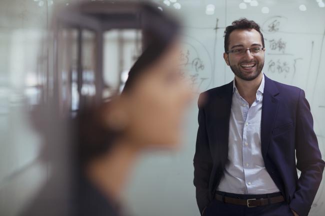 man in a suit standing in front of a whiteboard and smiling
